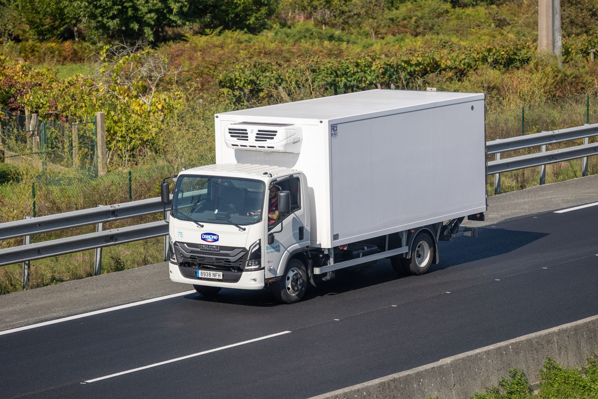 Three brightly colored semi-trucks parked side-by-side, green, blue and maroon, in a gravel lot.