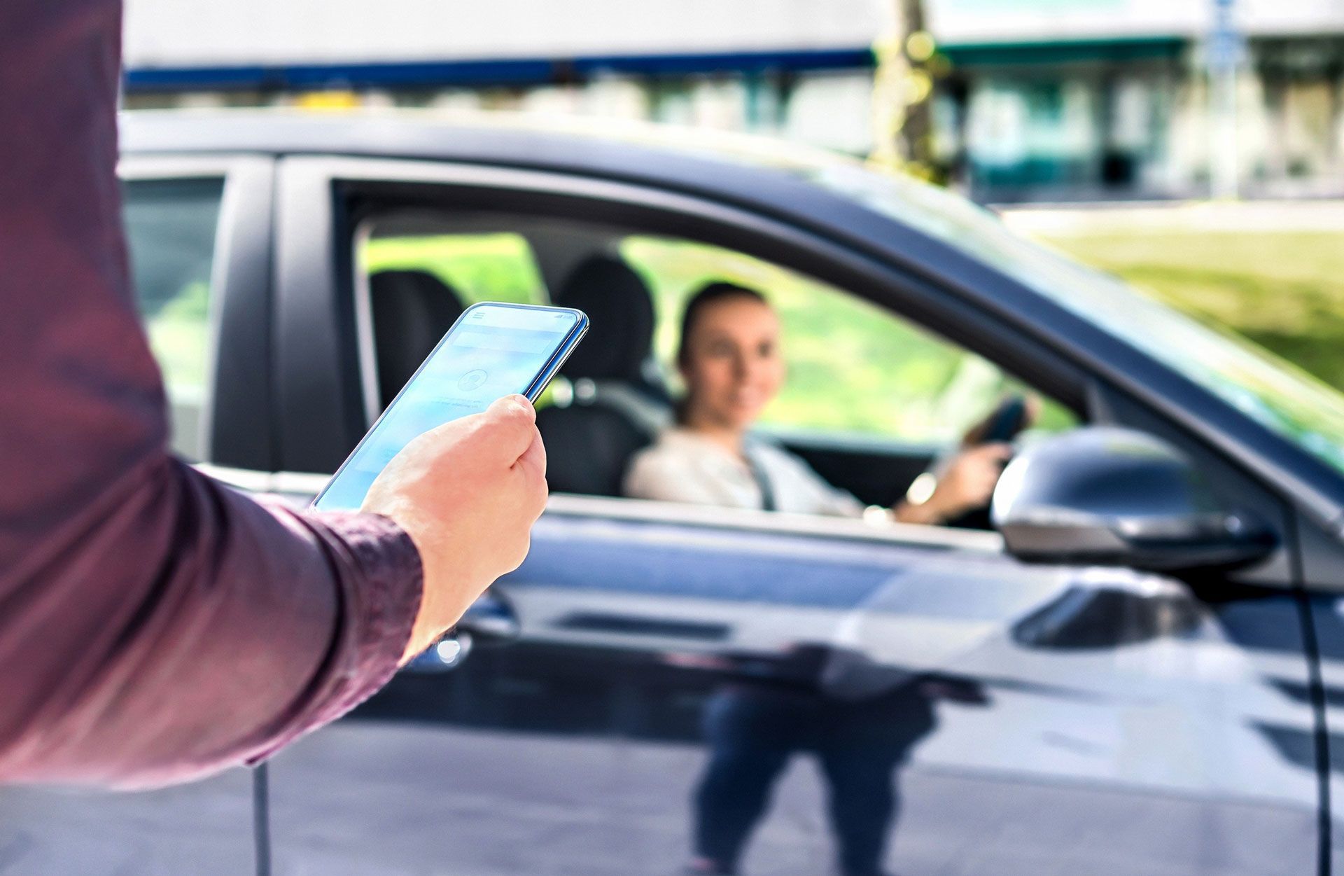 Person holding a phone near a car window with a driver inside.
