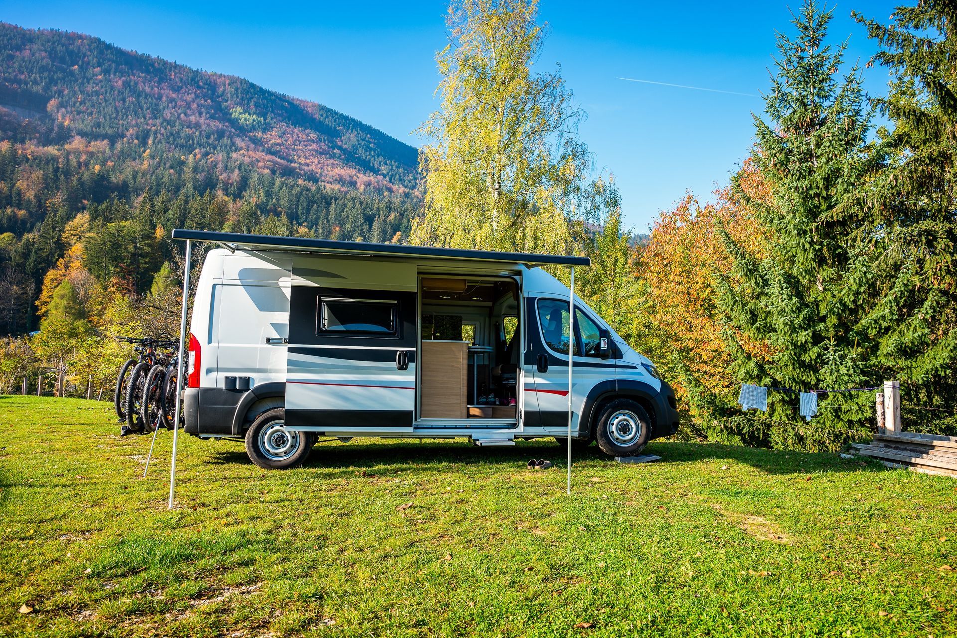 Camper van parked in a grassy area with open awning.