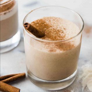 Glass of creamy, tan-colored drink, topped with cinnamon and cinnamon stick.