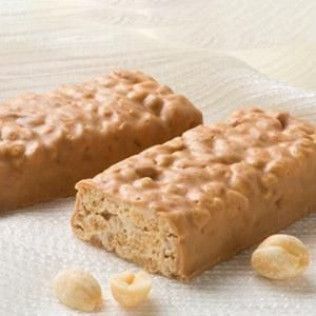 Two peanut butter bars on a white surface with scattered nuts.