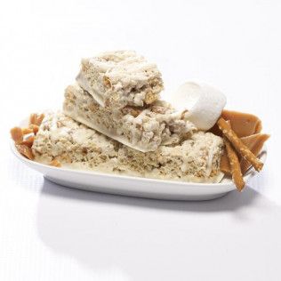 White dessert bars on an oval plate, with caramel pieces, pretzels, and a marshmallow.
