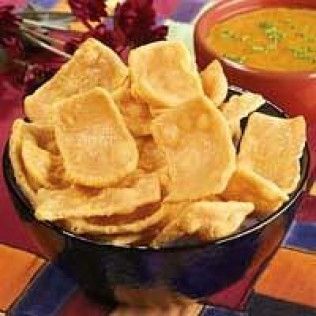 Bowl of golden, crispy papadums with a side of orange soup.