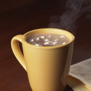 Yellow mug filled with hot chocolate and marshmallows, steam rising.