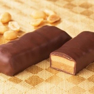 Chocolate-covered candy bars, one cut to reveal a peanut butter center, with scattered peanuts.