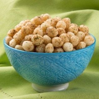 Blue bowl of seasoned puffed snacks on a green surface.
