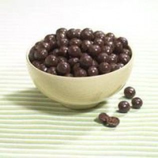 Bowl of chocolate-covered coffee beans on a green-striped surface.