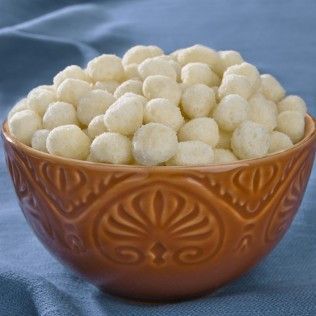 Bowl of white, ball-shaped snacks in a brown decorative bowl on a blue cloth.