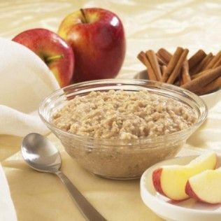 Bowl of oatmeal with apples and cinnamon sticks.