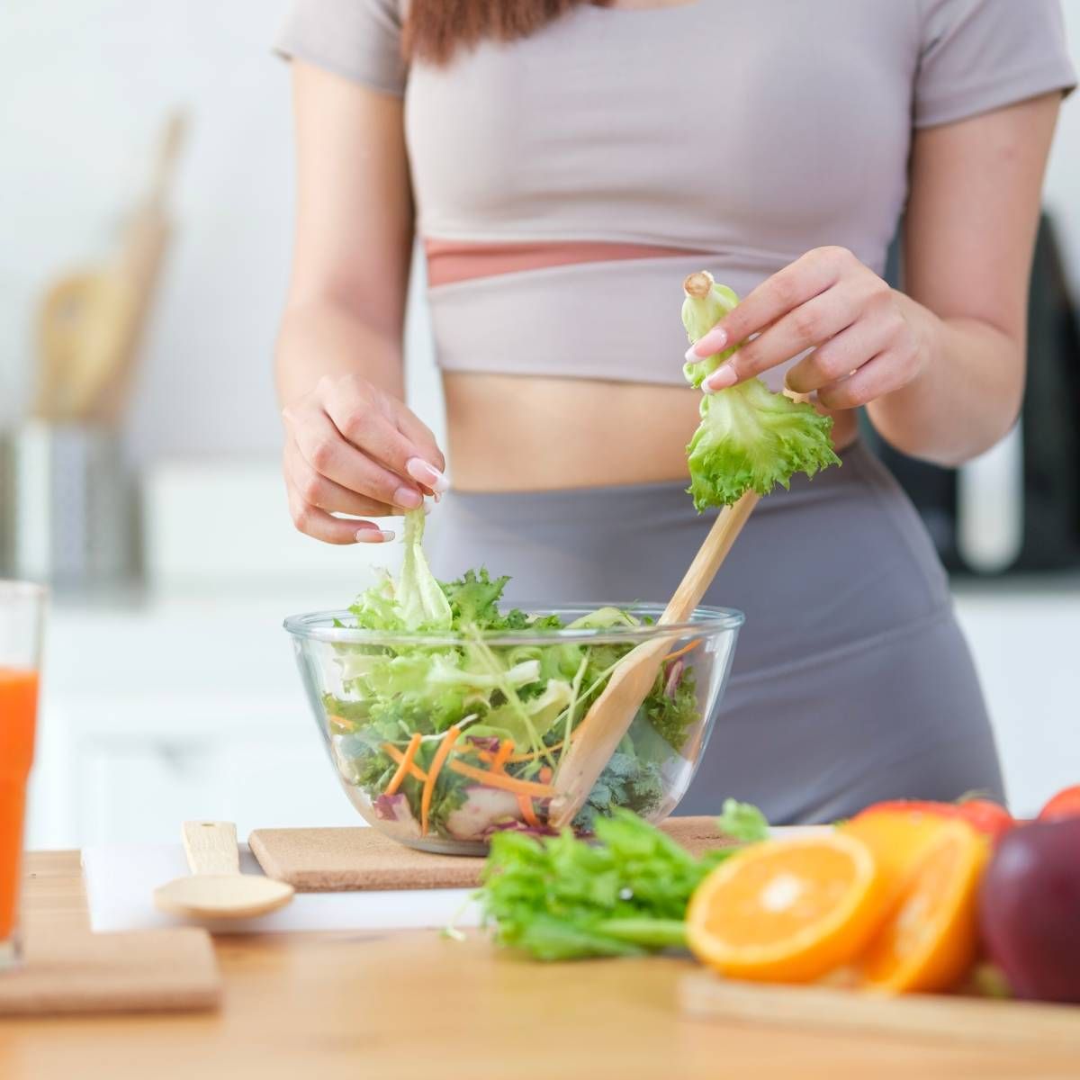Woman in athletic wear preparing a salad with fresh vegetables.