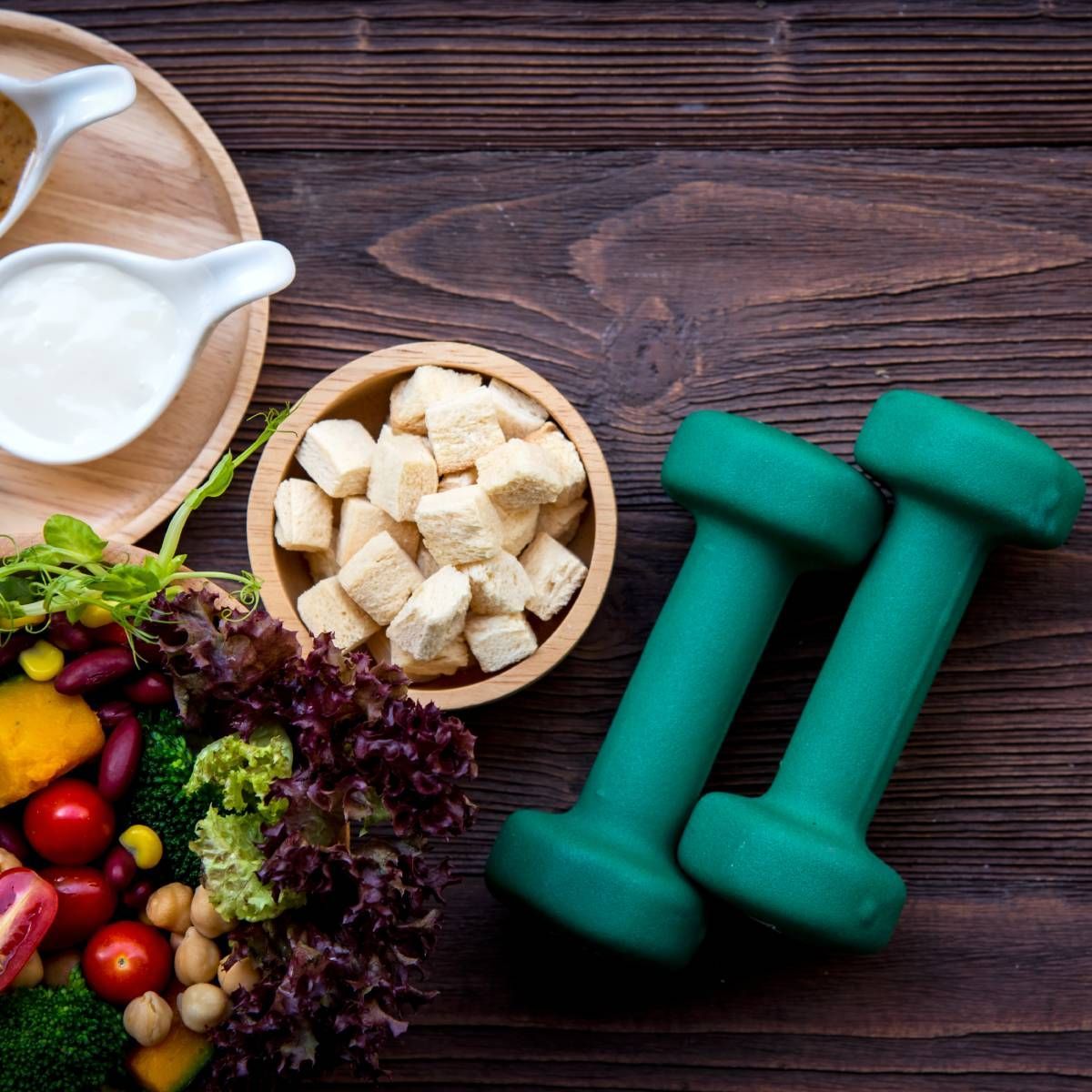 Healthy food, dumbbells, and fitness lifestyle on a wooden table.