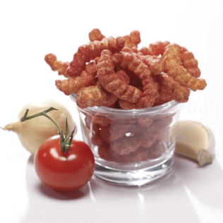 Cheetos in a glass with a tomato, onion, and garlic clove.