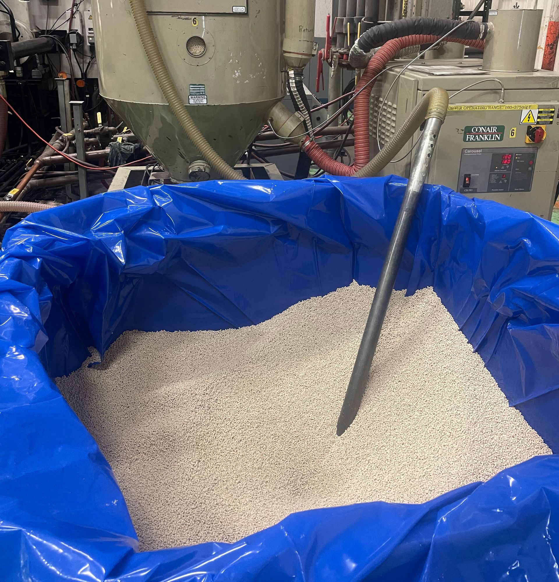 a container filled with resin and a hose that is pulling the resin into the molder