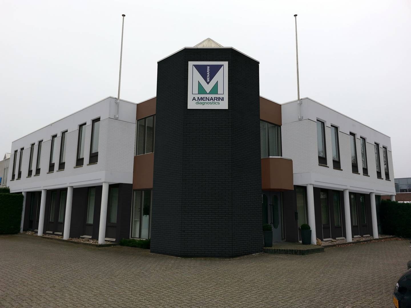 Modern kantoorgebouw van twee verdiepingen met een donkere centrale gevel.