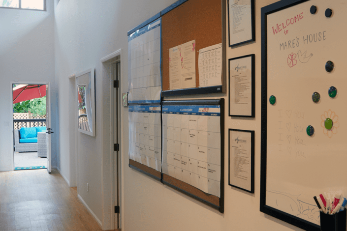 A hallway with a bulletin board and a white board on the wall.