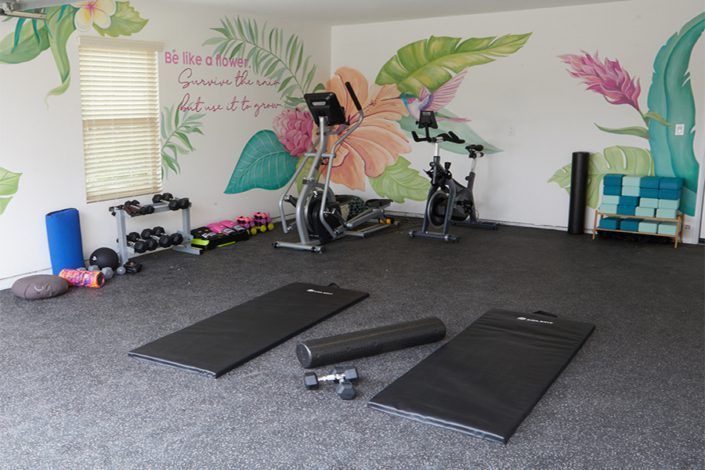 A gym with a mural on the wall and exercise equipment