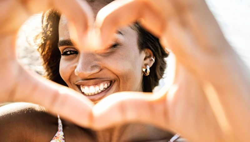 A woman is making a heart shape with her hands.