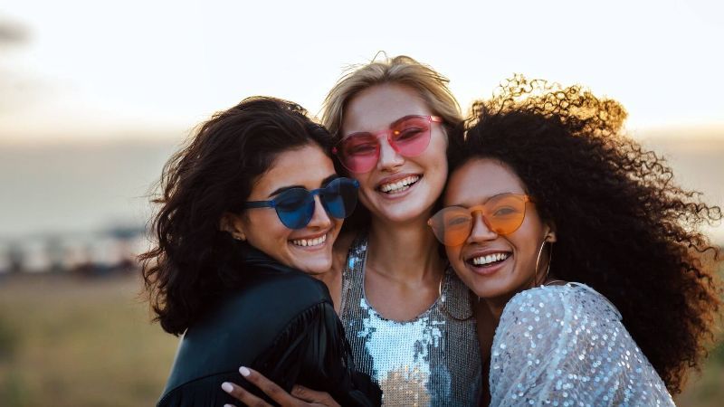 Three women wearing sunglasses are posing for a picture together.