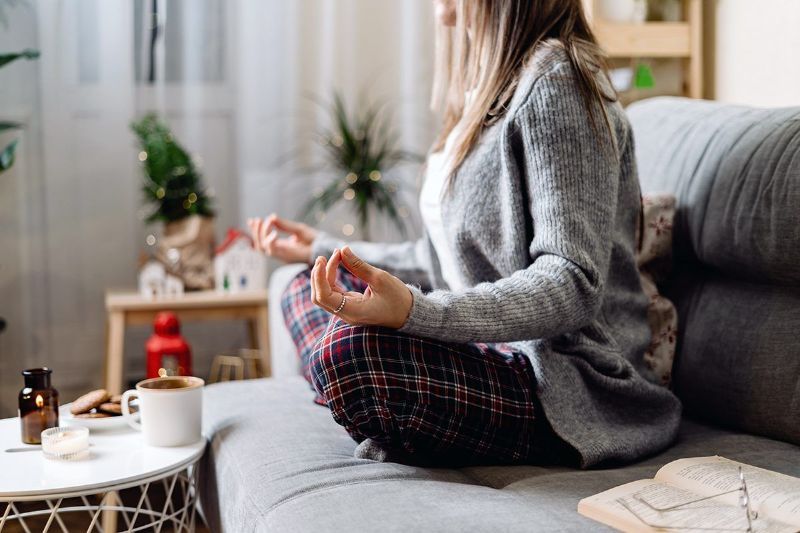 A woman is sitting on a couch meditating.