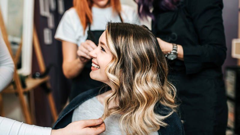 A woman is getting her hair done by a hairdresser in a salon.