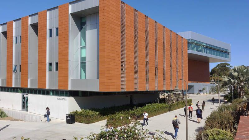 A group of people are walking in front of a San Diego school building.