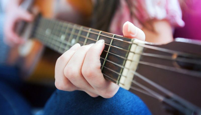 A close up of a person playing an acoustic guitar.