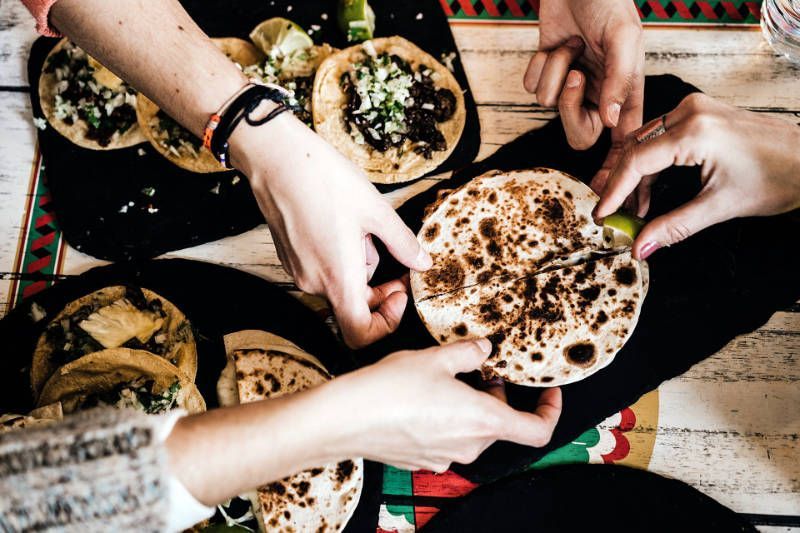 A group of people are eating tacos on a table.