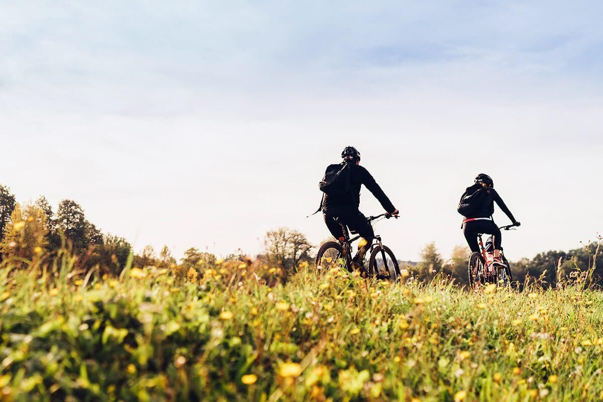 Two women riding bicycles in a field.