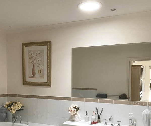 Bathroom Interior With a Large Mirror and a Bright Circular Light Fixture — Gold Coast Skylights in Slacks Creek, QLD