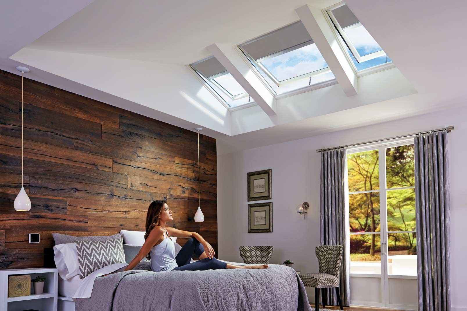 Woman Sitting on a Bed in a Bright Bedroom With Skylights — Gold Coast Skylights in Slacks Creek, QLD