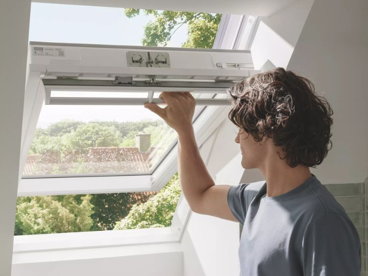 Man Opening a Skylight in a White Room With a View of Trees and Rooftops — Gold Coast Skylights in Nerang, QLD
