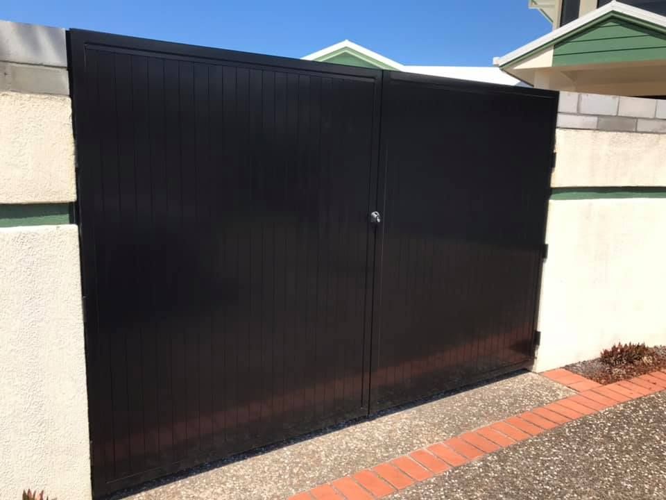 A Black Garage Door is Sitting Next to a Brick Wall — Jensen Welding & Fabrication in Caloundra, QLD