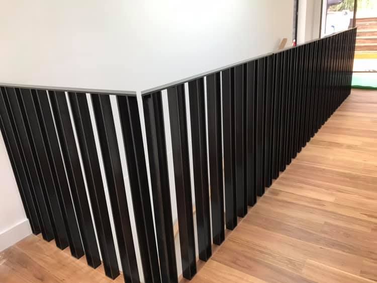 A Black Railing is Surrounding a Wooden Floor in a Room — Jensen Welding & Fabrication in Chevallum, QLD