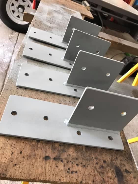 A Row of Metal Brackets Sitting on Top of a Wooden Table — Jensen Welding & Fabrication in Chevallum, QLD