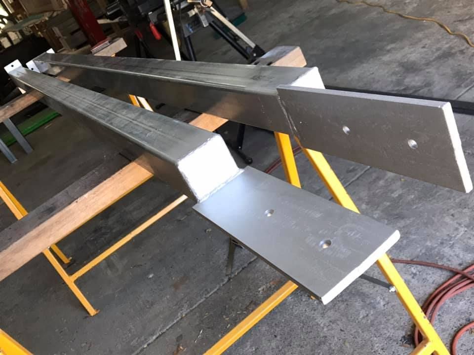 Two Pieces of Metal Are Sitting on a Yellow Stand — Jensen Welding & Fabrication in Chevallum, QLD