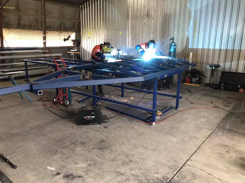 A Group of People Are Welding a Metal Structure in a Garage — Jensen Welding & Fabrication in Chevallum, QLD