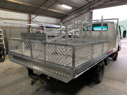 Silver flatbed truck with metal side rails inside an industrial warehouse. — Jensen Welding & Fabrication in Chevallum, QLD