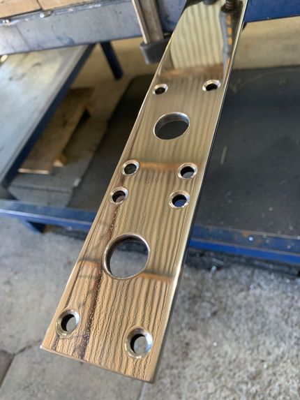 Perforated wooden strip with multiple drilled holes, resting on a workbench.  — Jensen Welding & Fabrication in Chevallum, QLD