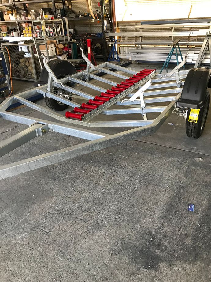 Silver boat trailer with red roller bunks in a garage or workshop  — Jensen Welding & Fabrication in Chevallum, QLD