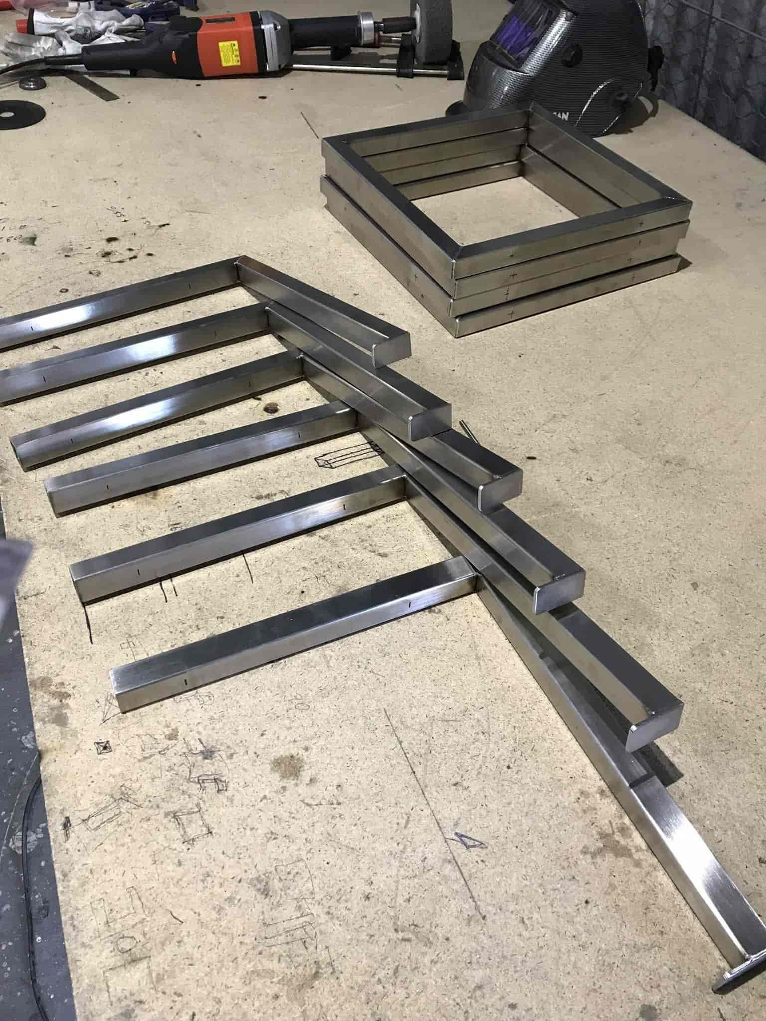 A Bunch of Metal Pieces Are Sitting on Top of a Wooden Table — Jensen Welding & Fabrication in Chevallum, QLD