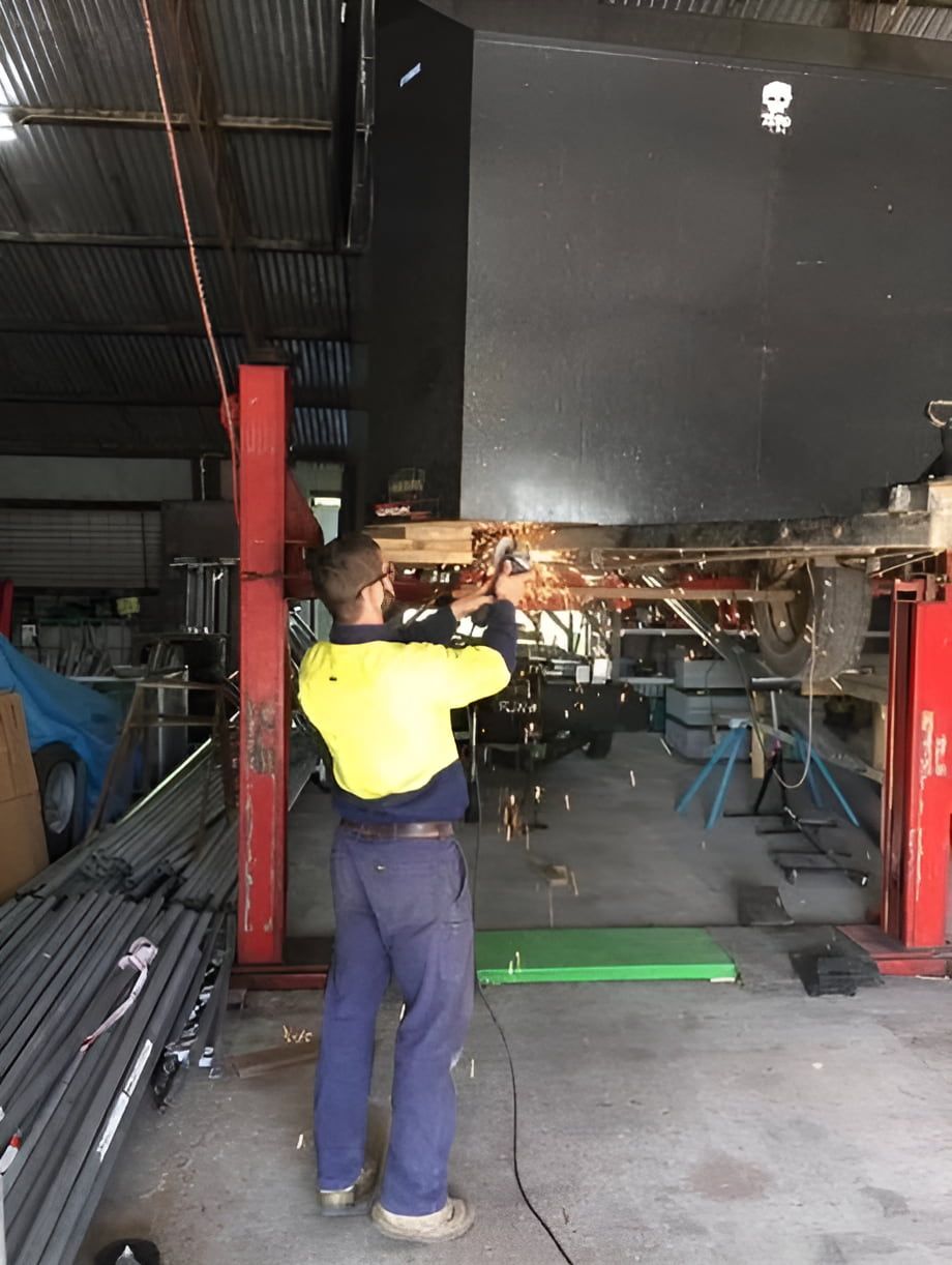 A Man is Welding a Piece of Metal in a Garage — Jensen Welding & Fabrication in Chevallum, QLD