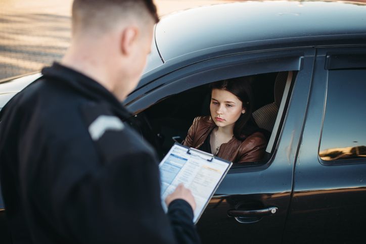 A police officer is talking to a woman in a car.