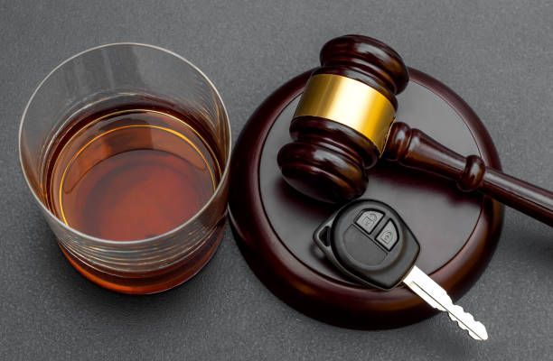 A glass of alcohol next to a judge 's gavel and car key