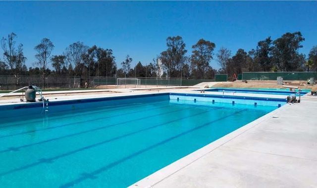 Una gran piscina con árboles al fondo.
