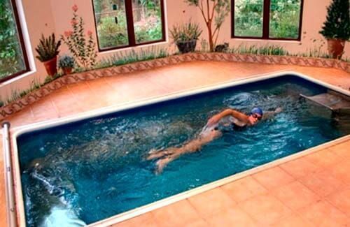 Una mujer está nadando en una gran piscina cubierta.