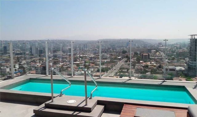 Una gran piscina en lo alto de un edificio con una ciudad al fondo.