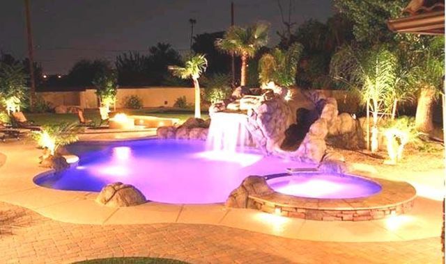 Una gran piscina se ilumina por la noche con luces violetas.