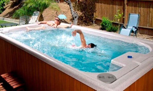Un hombre está nadando en un jacuzzi mientras una mujer está acostada en el costado.