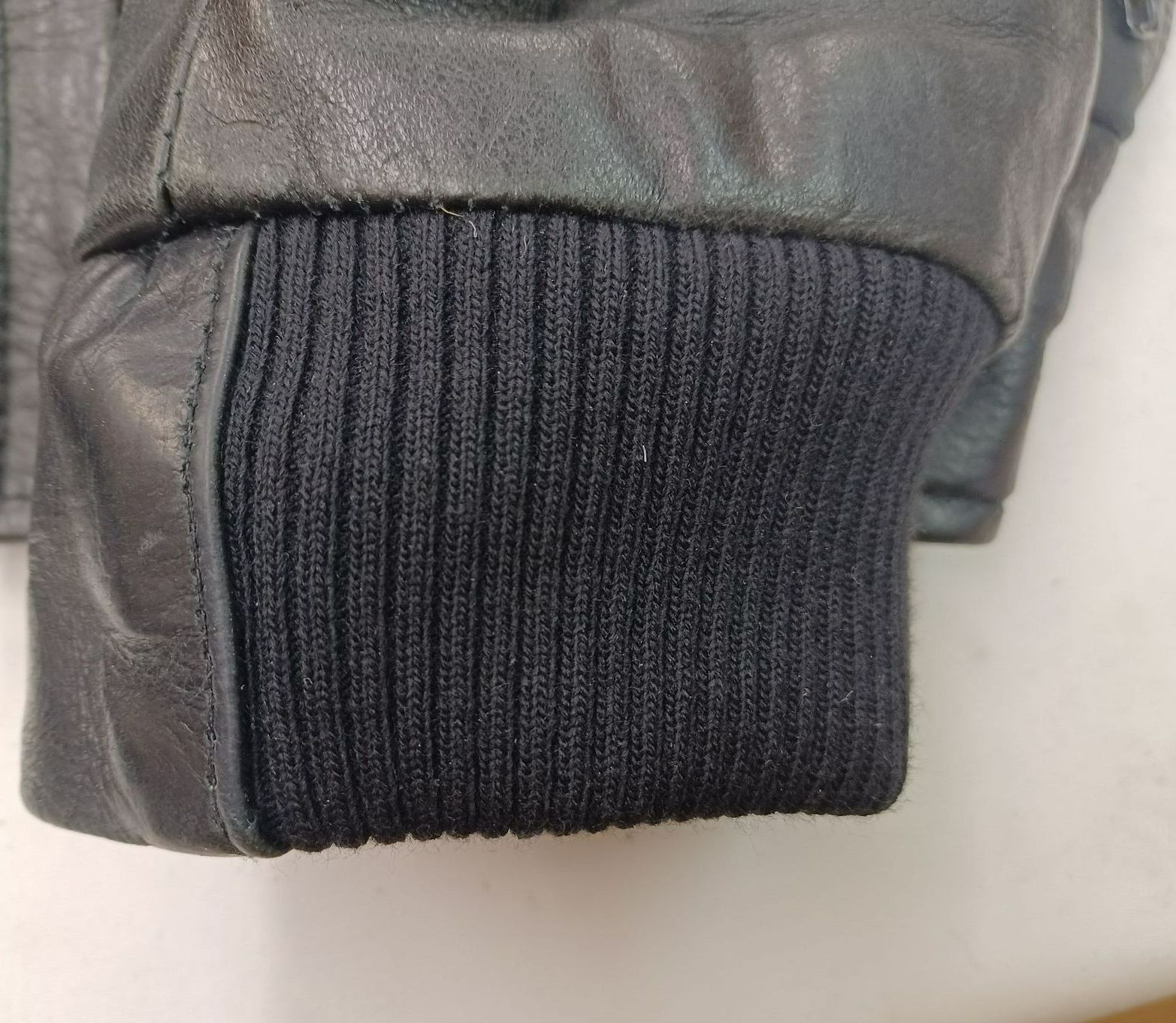 Un gros plan d'une veste en cuir noir avec un poignet en tricot noir.