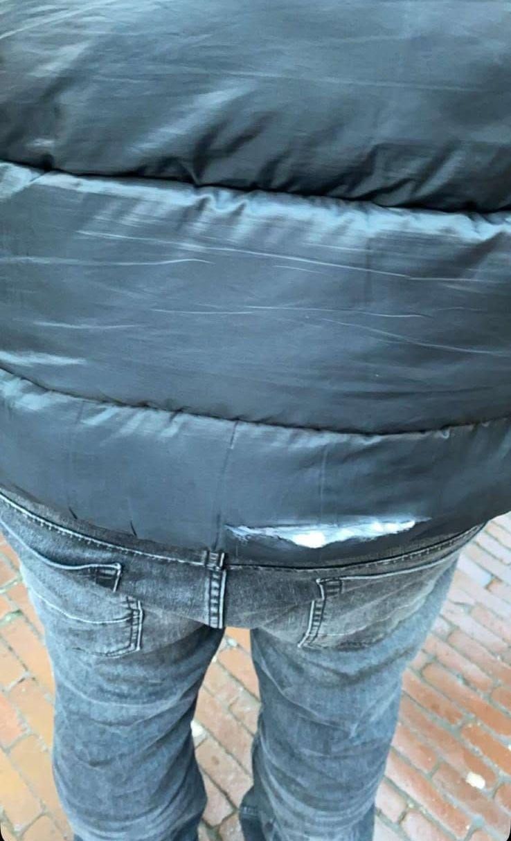 Le dos d'une personne portant une veste noire et un jean.